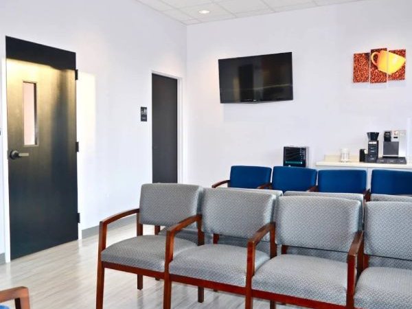 Waiting room with rows of upholstered chairs and a coffee station
