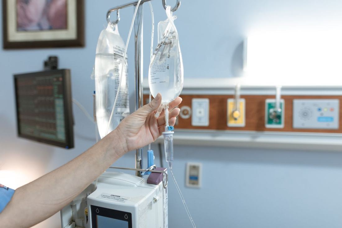 A clinician adjusts an IV fluid bag