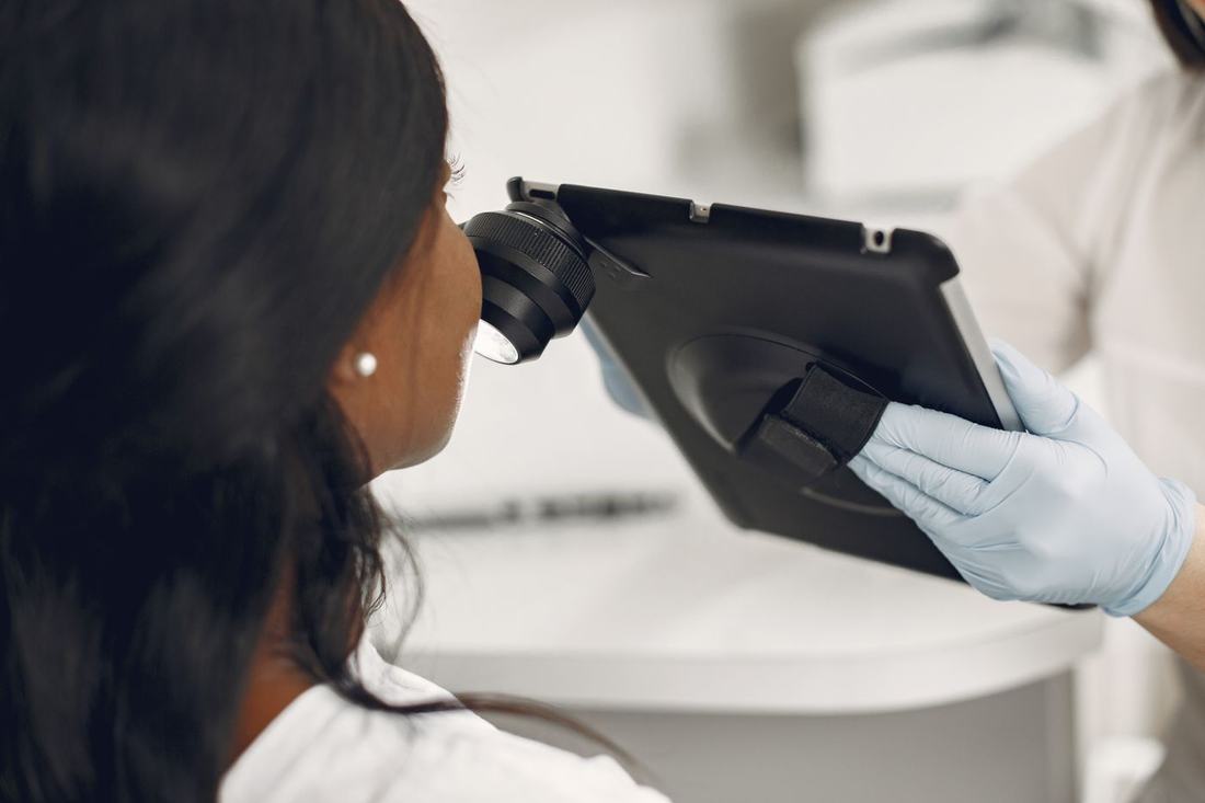 A clinician examines skin with a dermatoscope